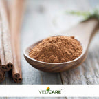 Wooden spoon filled with cinnamon powder on a wooden surface, with Vedicare logo at the bottom.