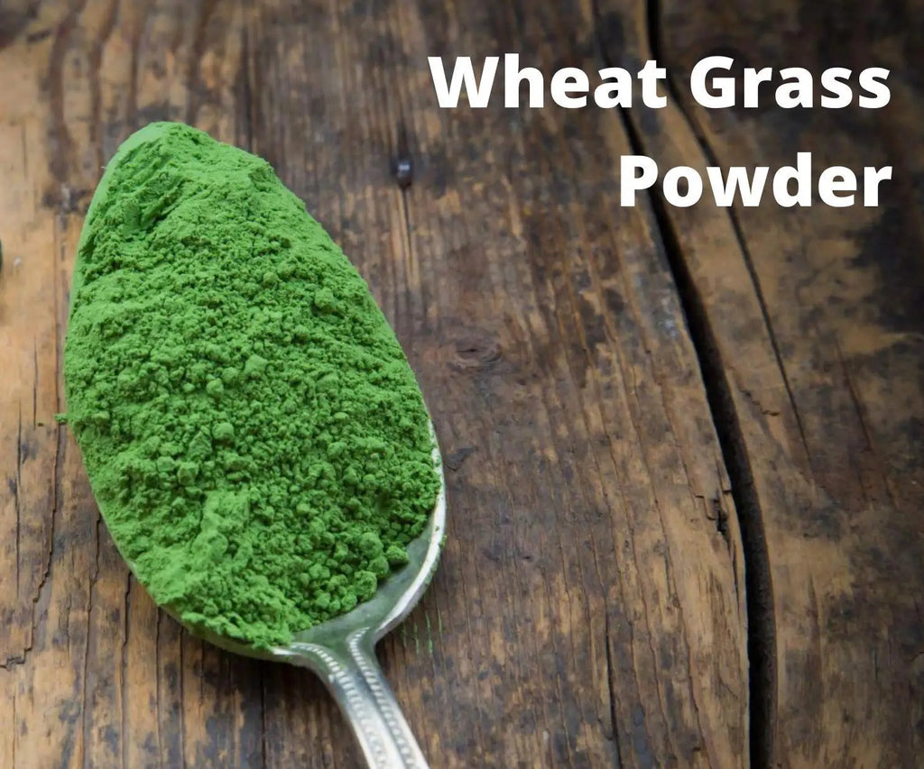 Spoonful of wheat grass powder on a wooden surface with text 'Wheat Grass Powder'.