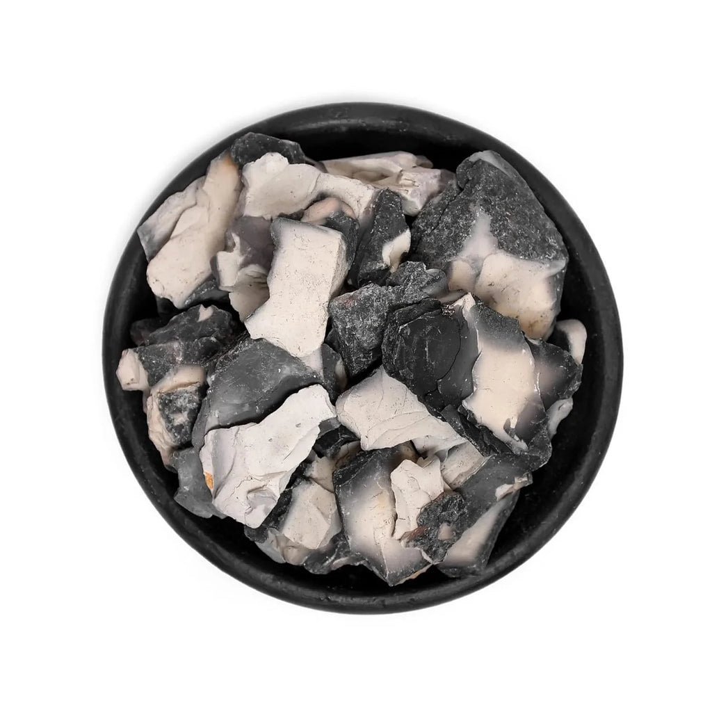 Black and white stone chips in a black bowl on a white background